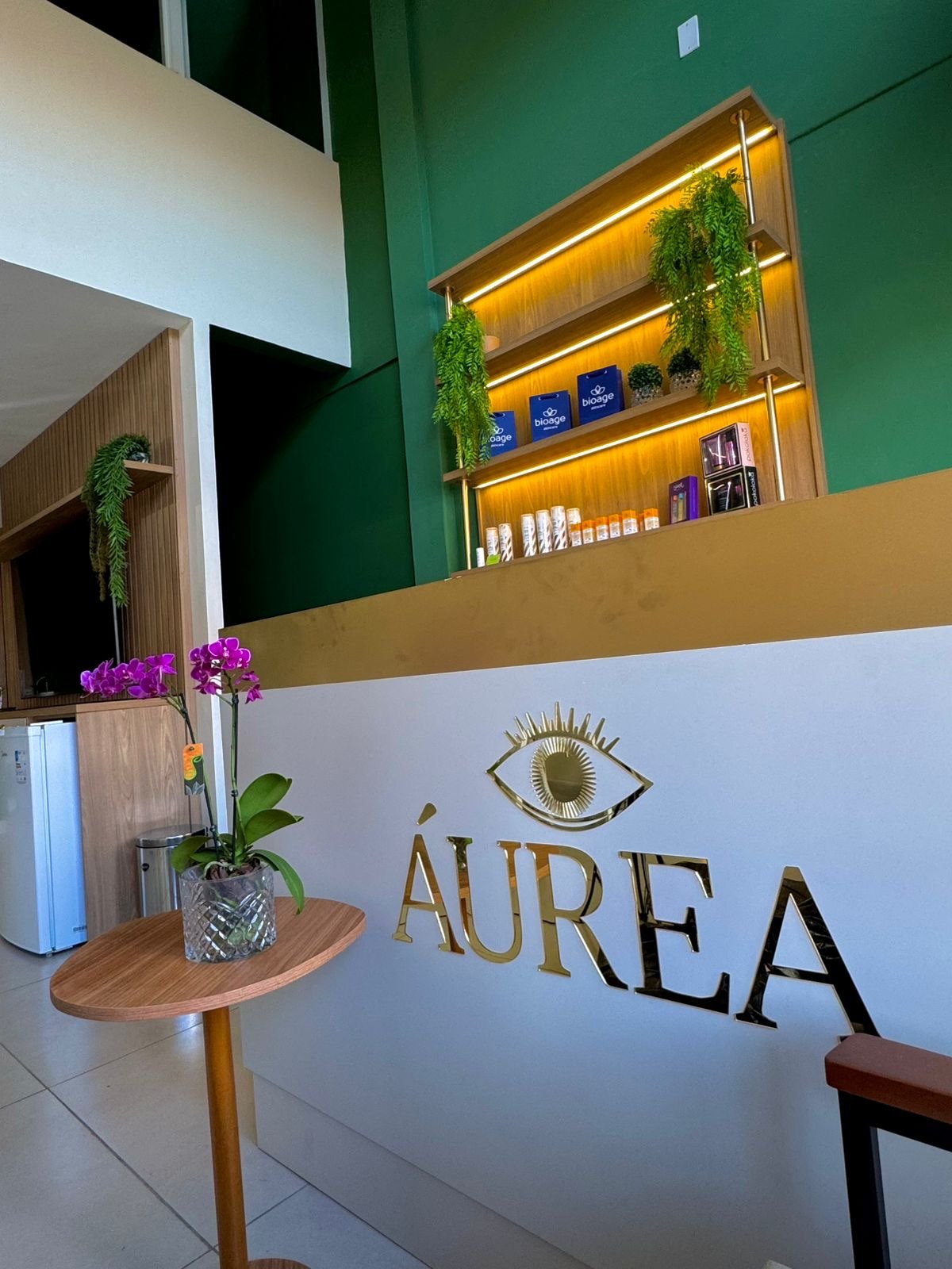 Recepção da Áurea, com o letreiro dourado da marca e a prateleira de produtos Bioage